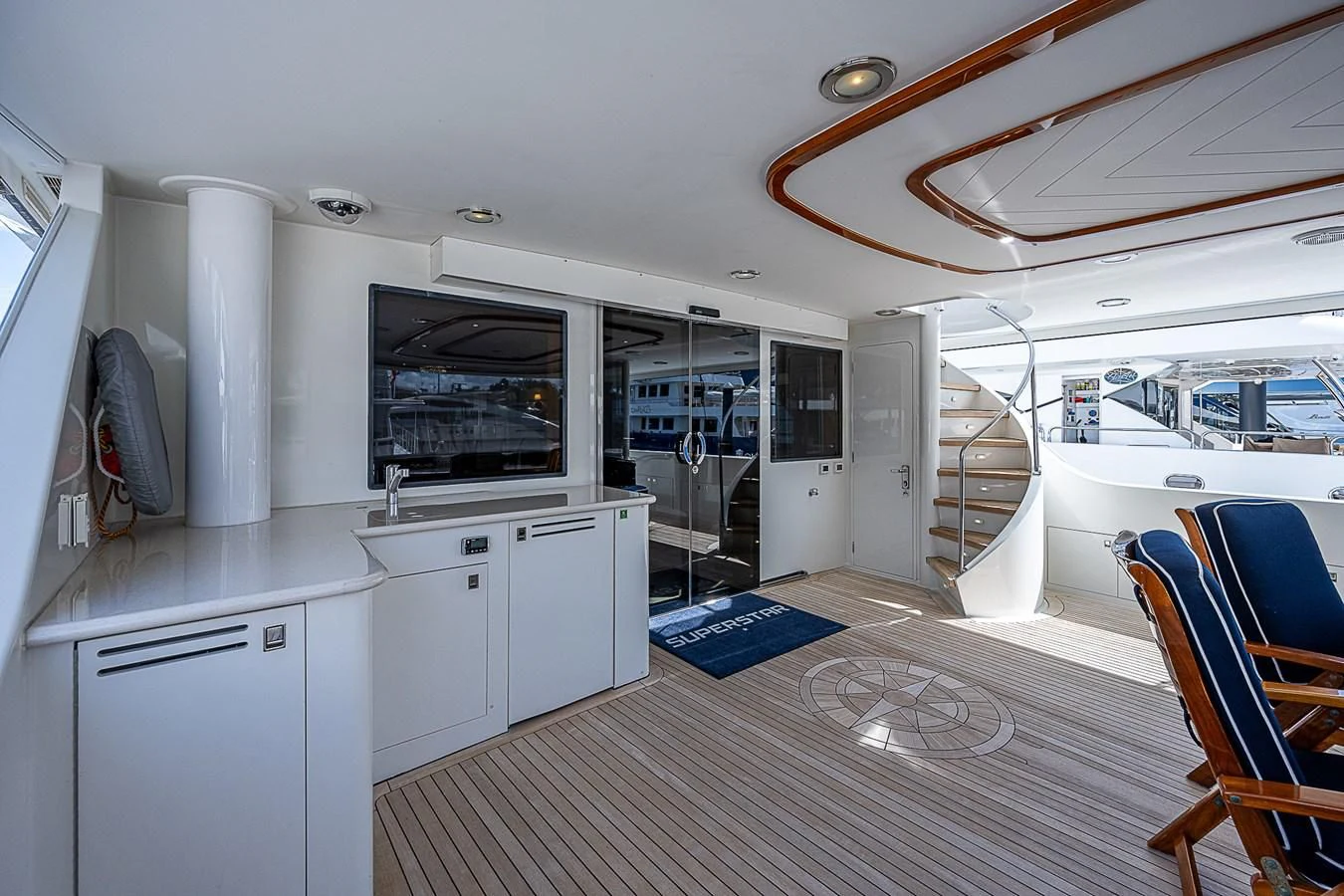 a room with a large window and a table with chairs and a television aboard SUPERSTAR Yacht for Charter