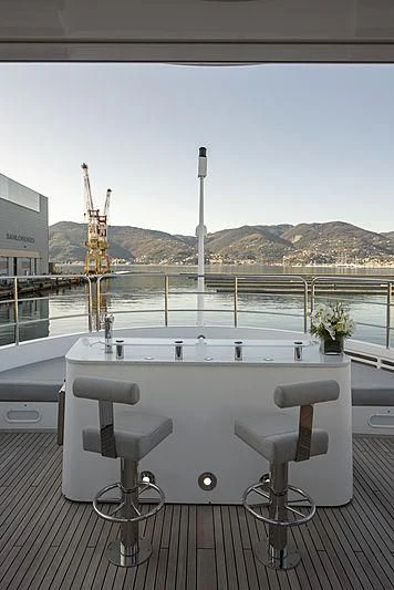a white table with a white table and chairs on a deck with a view of a city and aboard TAYRONA Yacht for Sale