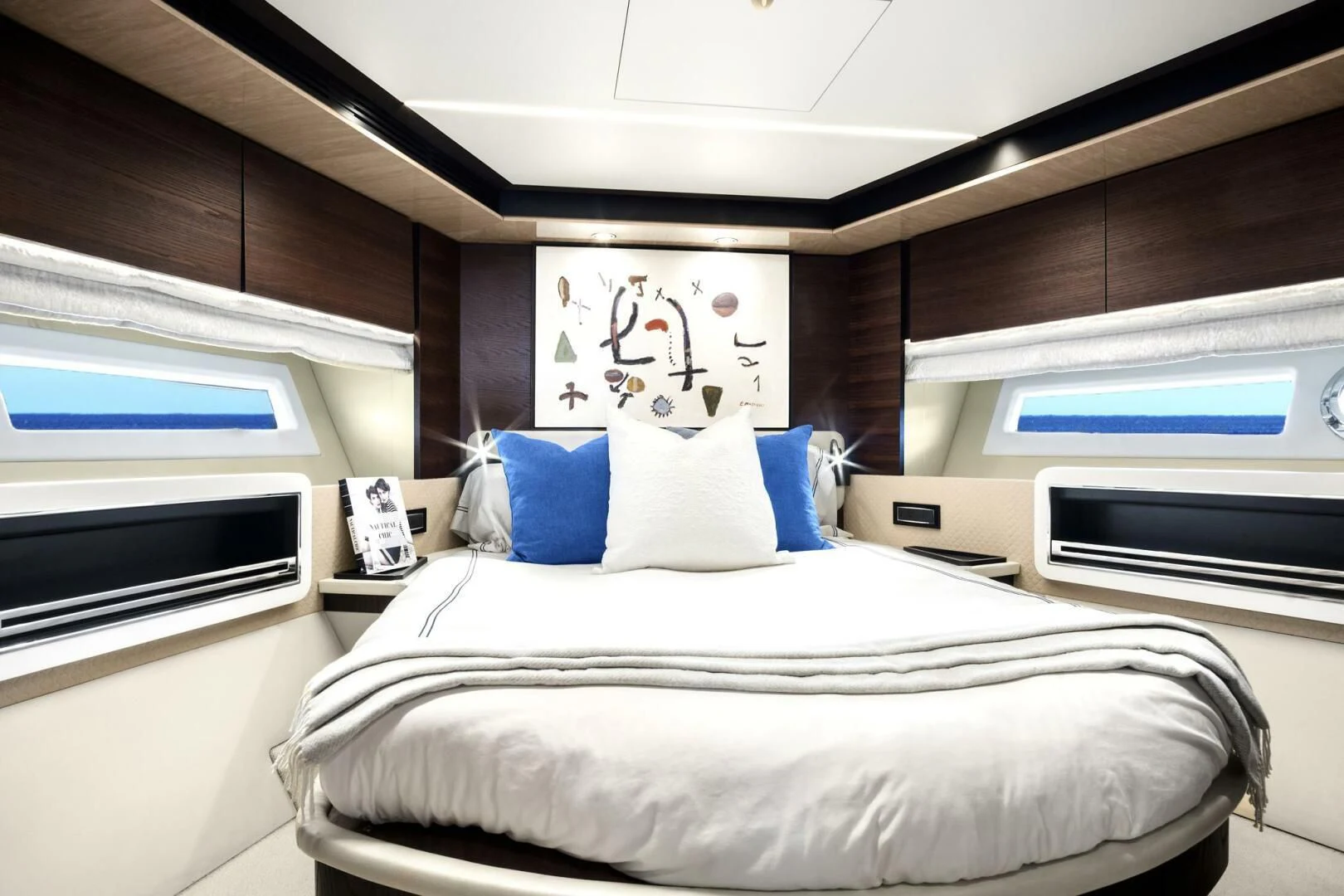 a bed with a white sheet and blue pillows aboard GRATITUDE Yacht for Sale