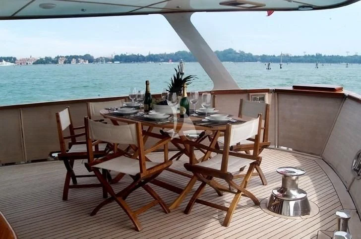 a table set for dinner on a deck overlooking a body of water aboard LA VOGLIA MATTA Yacht for Charter