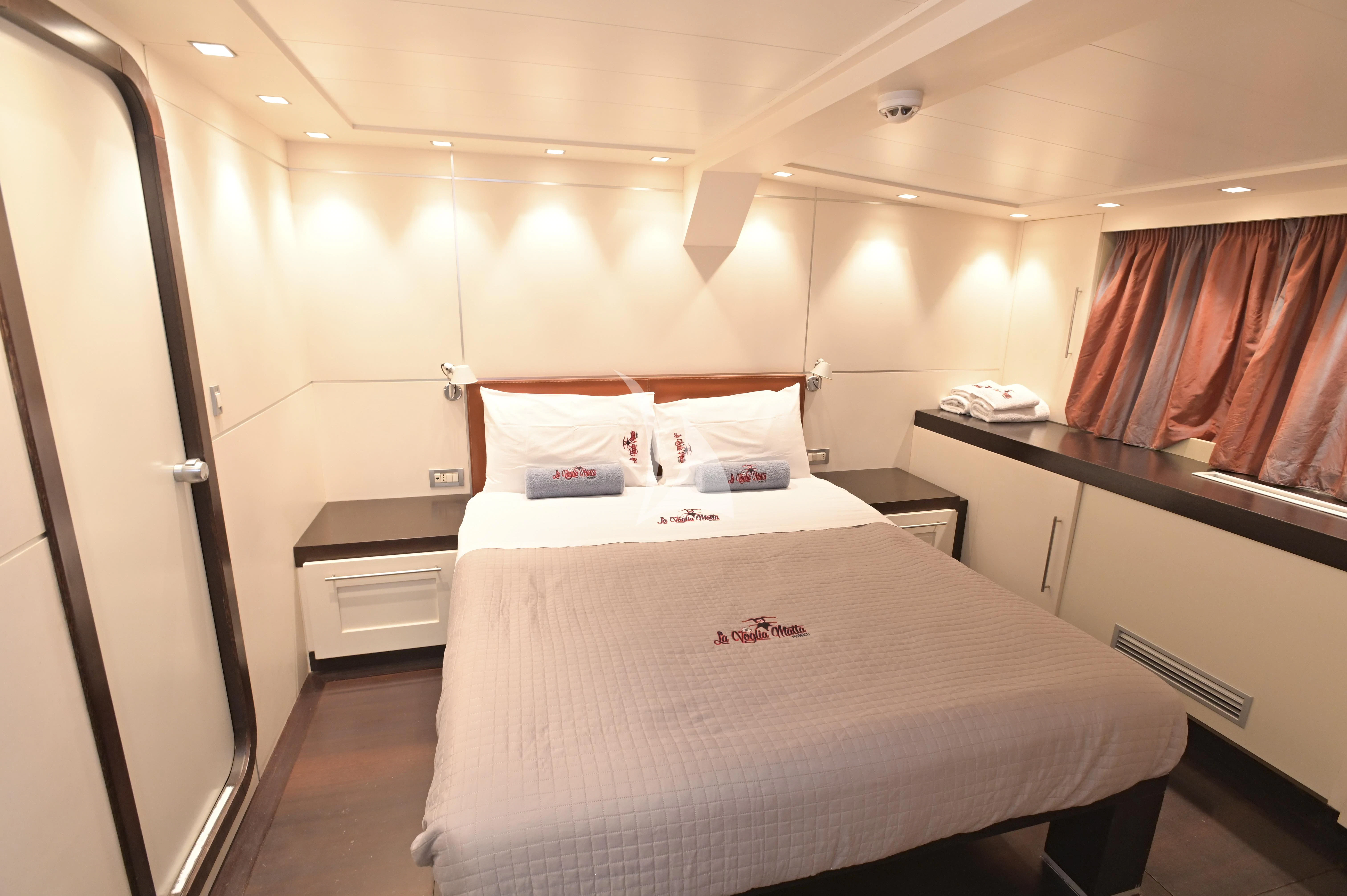 a room with a bed and desk aboard LA VOGLIA MATTA Yacht for Charter