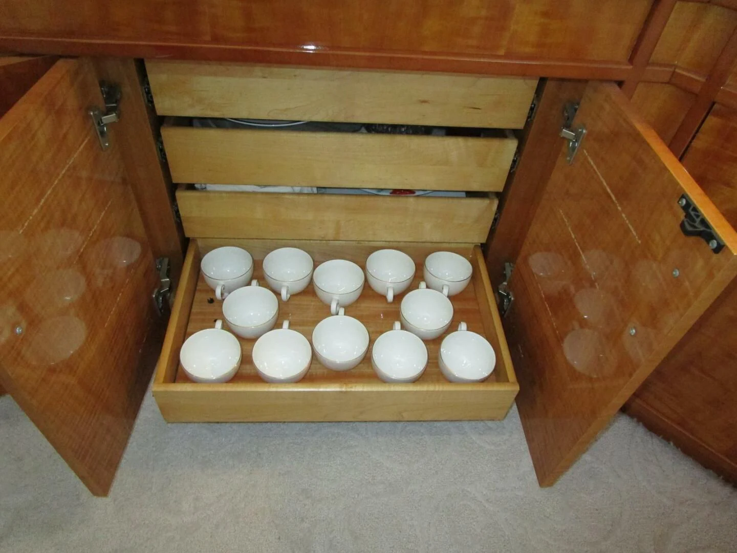 a wooden cabinet with white cups aboard CARPE DIEM Yacht for Charter