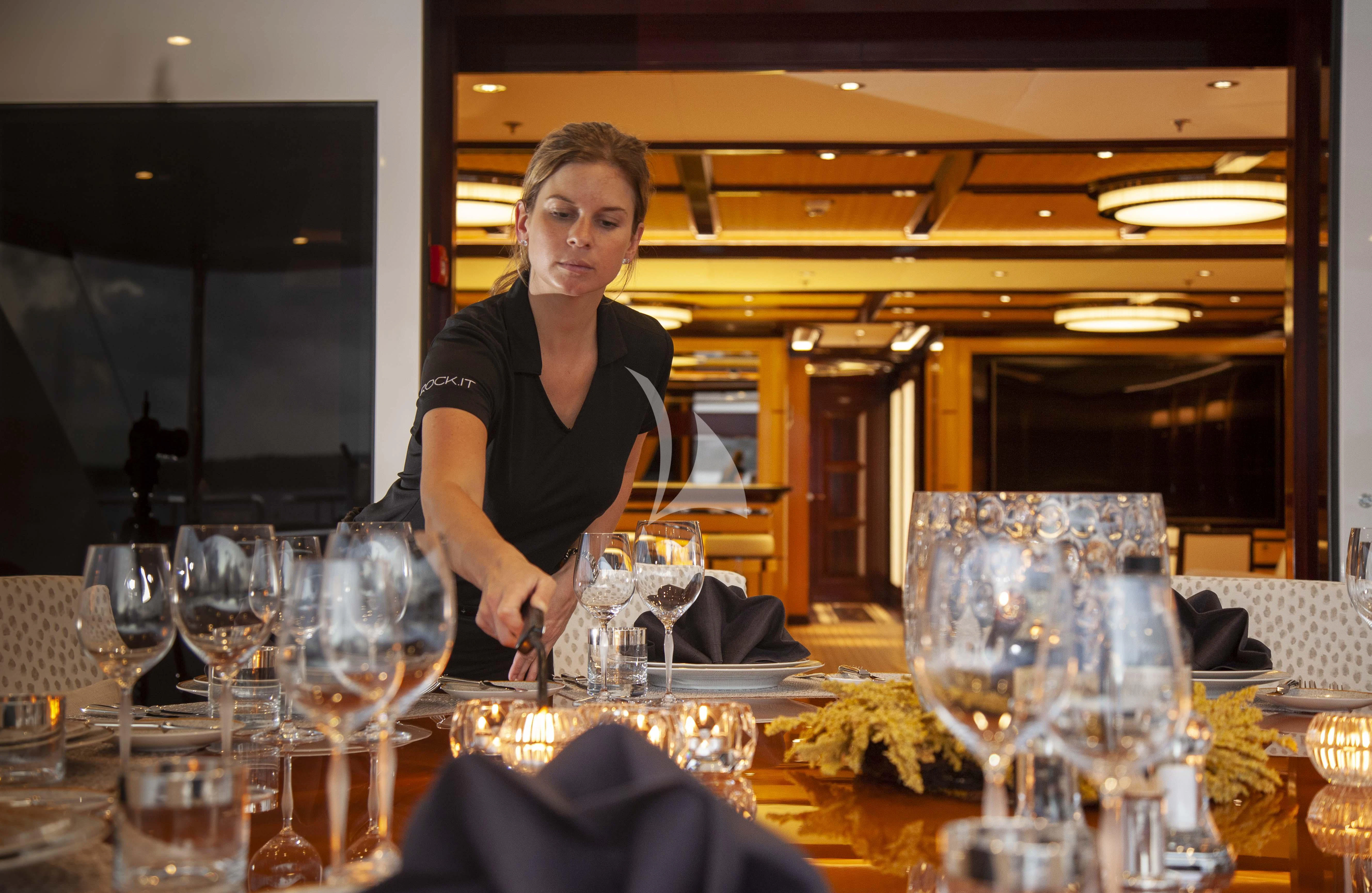 a person standing next to a table full of wine glasses aboard ROCK.IT Yacht for Charter