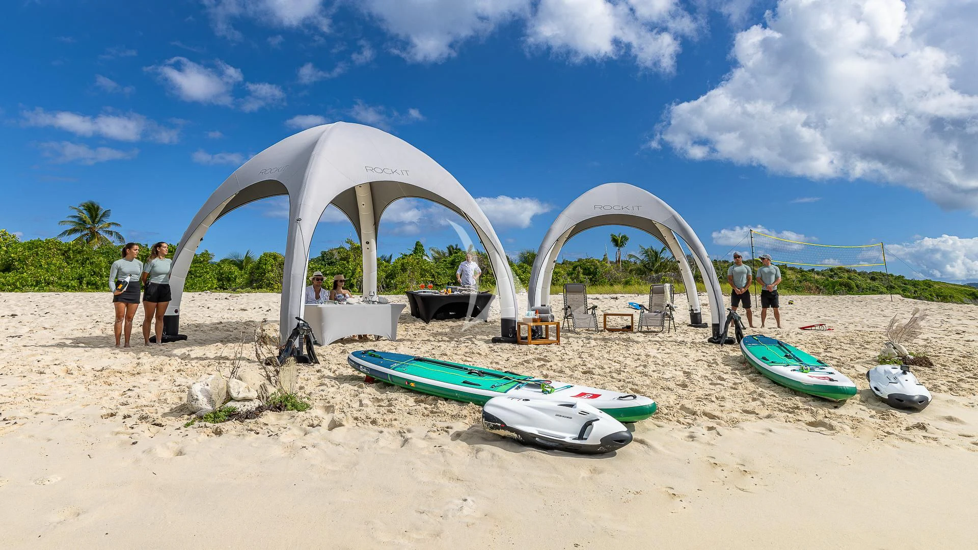 a group of people stand on a beach next to a large spherical structure aboard ROCK.IT Yacht for Charter