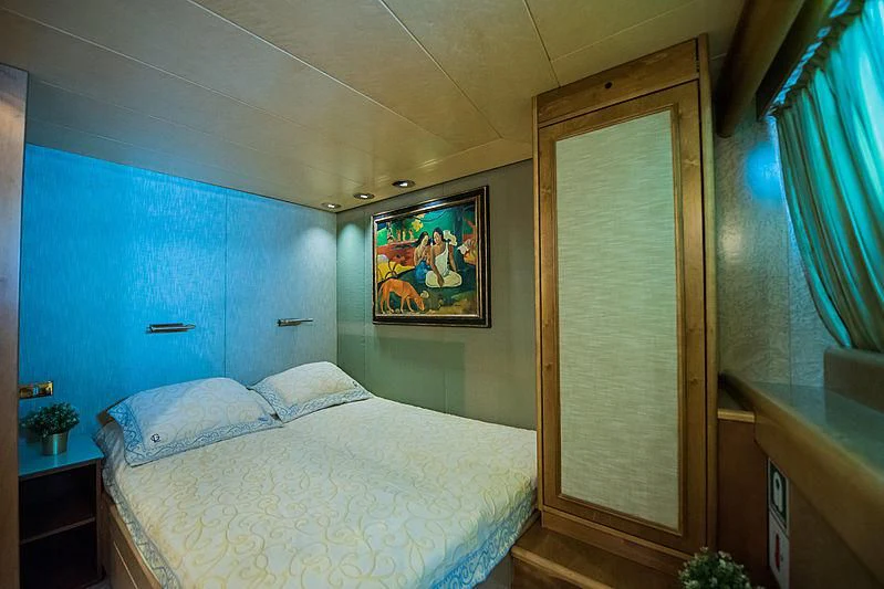 a bedroom with a bed and a painting on the wall aboard LADY RINA Yacht for Sale