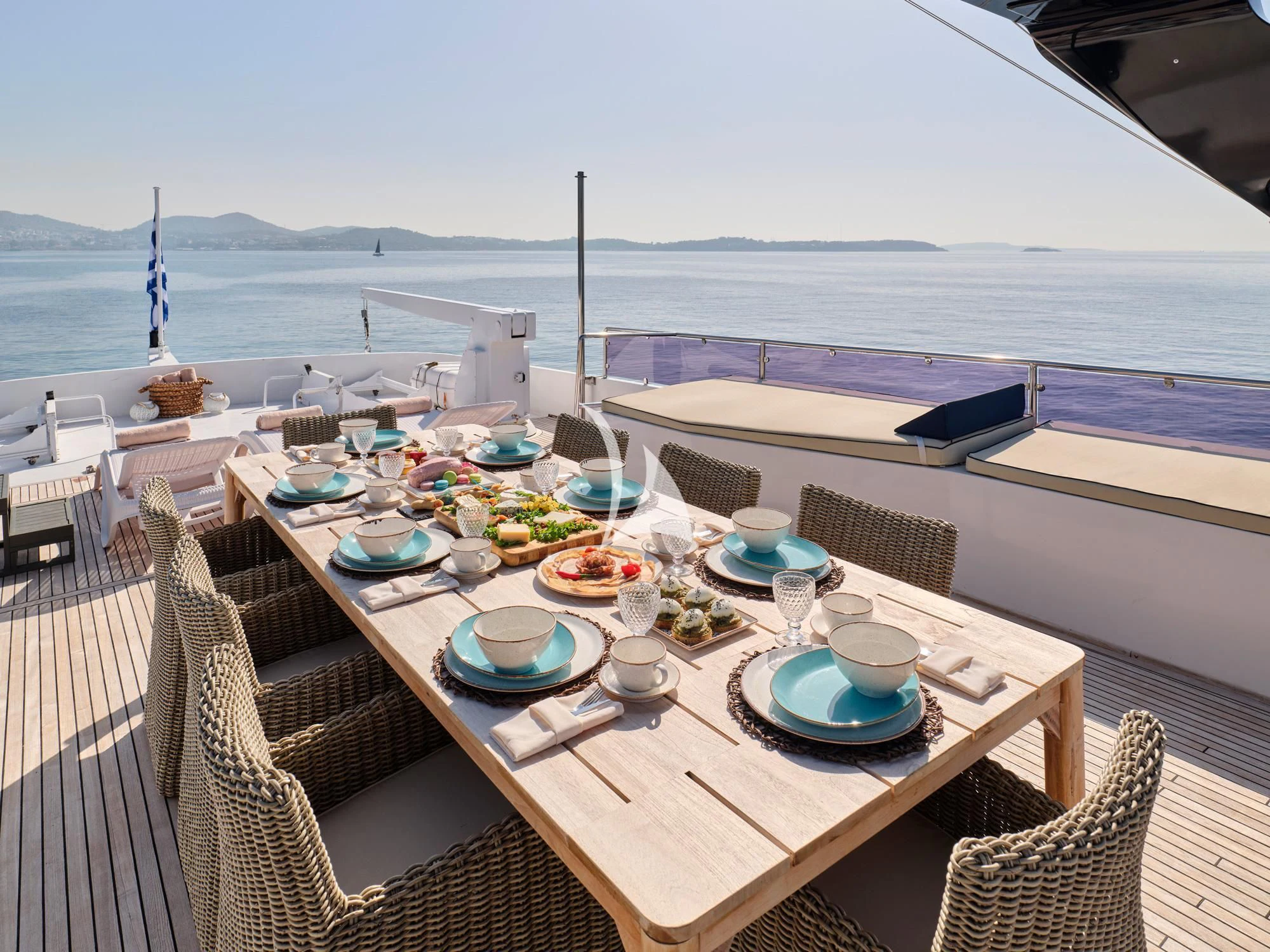a table with plates and cups on it on a deck with a body of water in the background aboard LADY RINA Yacht for Sale