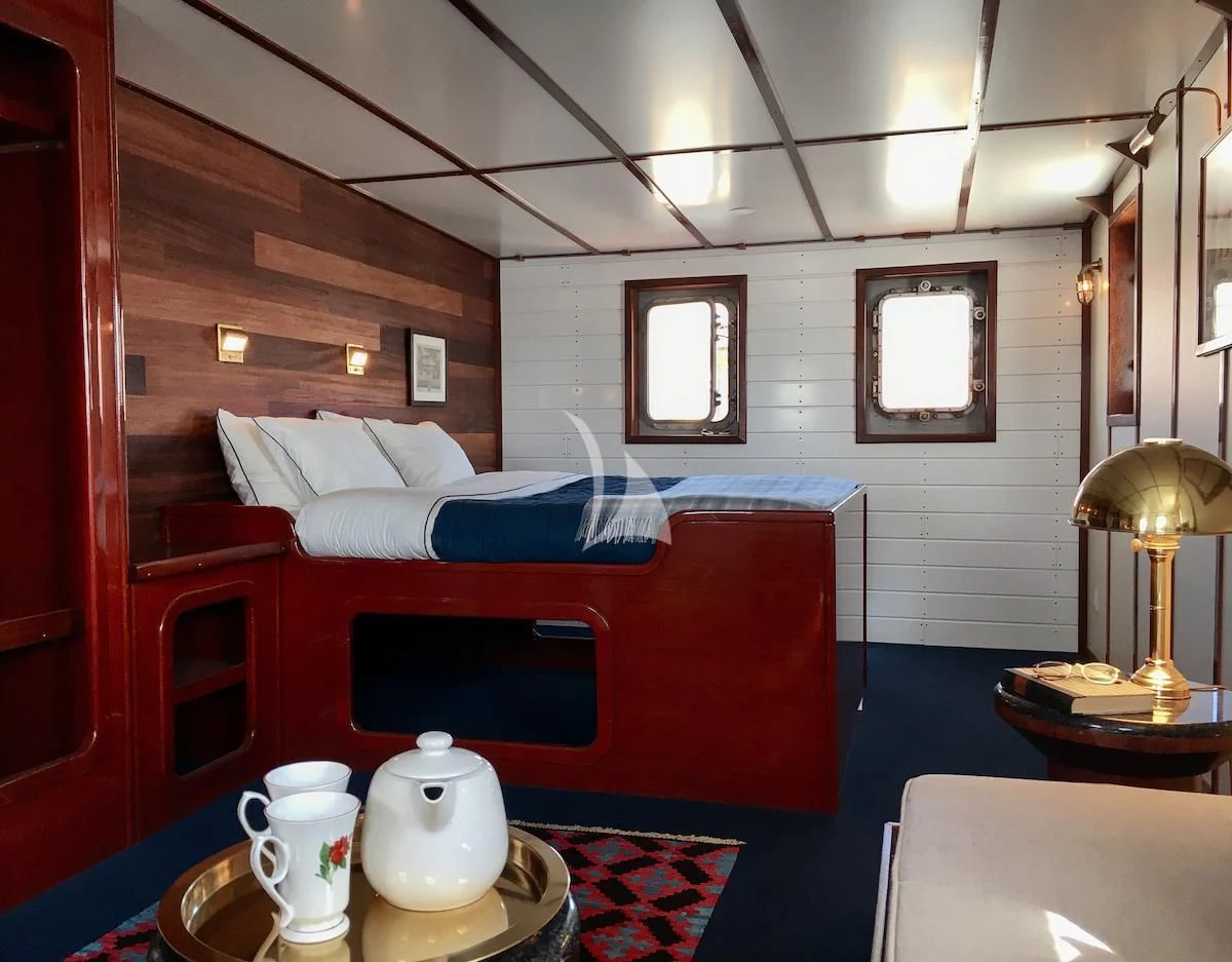 a room with a bed and coffee table aboard BALTO Yacht for Sale