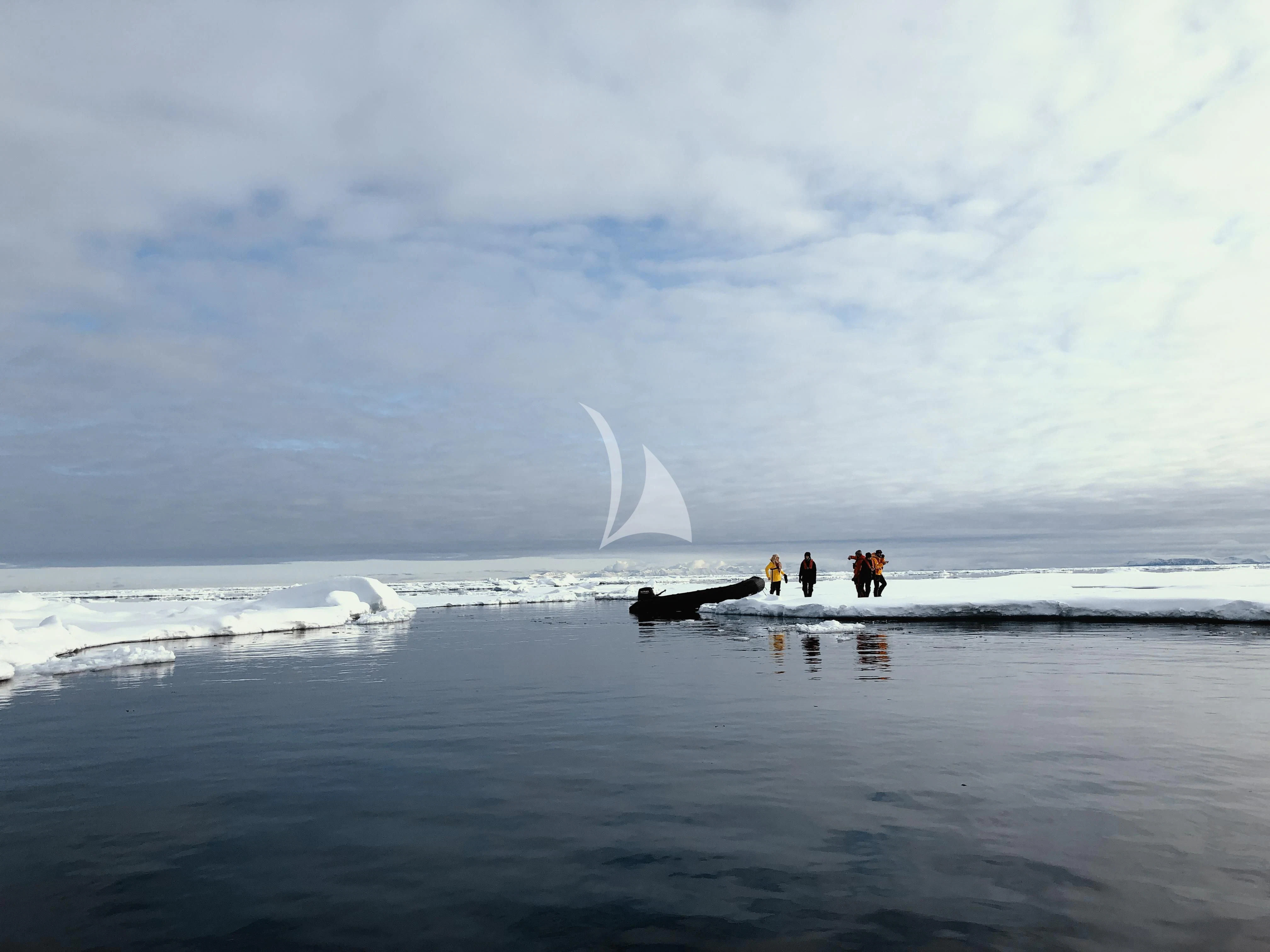 a group of people standing on a beach looking at a wave in the ocean aboard BALTO Yacht for Sale