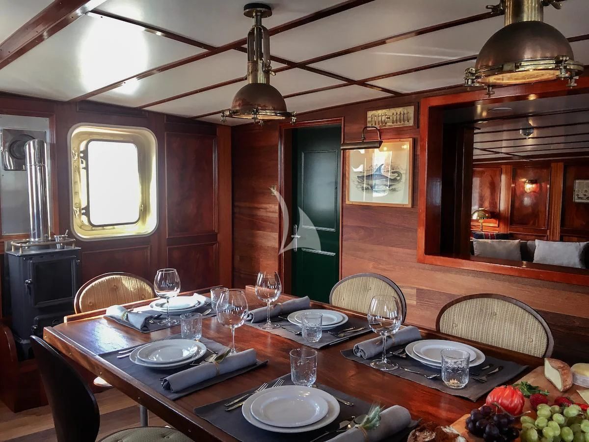 a dining table with plates and glasses aboard BALTO Yacht for Sale