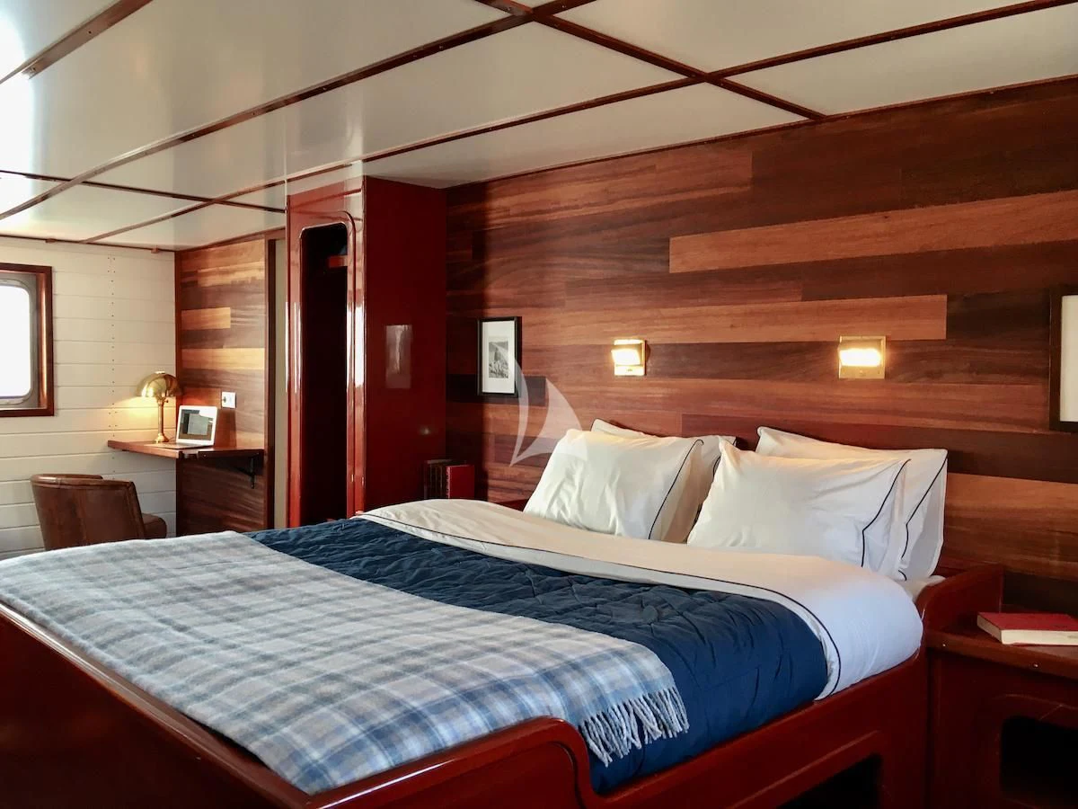 a bed with a blue comforter aboard BALTO Yacht for Sale