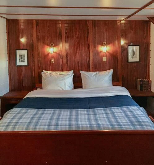 a bed with a blue and white striped bed spread aboard BALTO Yacht for Sale