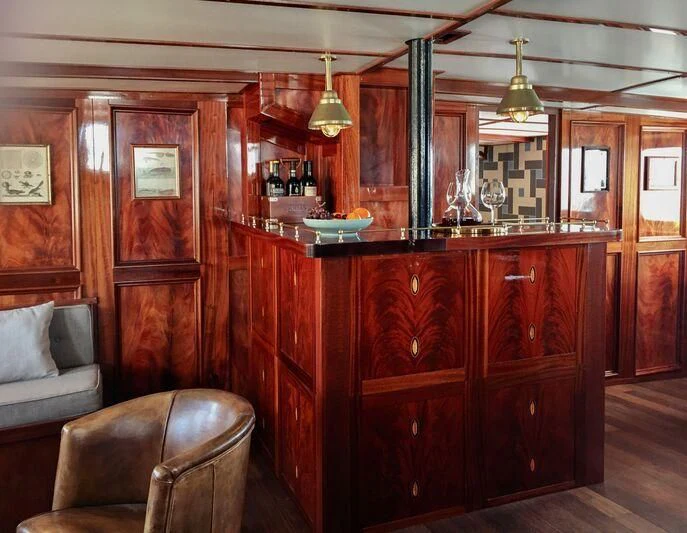 a room with a wood cabinet and a chair and a table aboard BALTO Yacht for Sale
