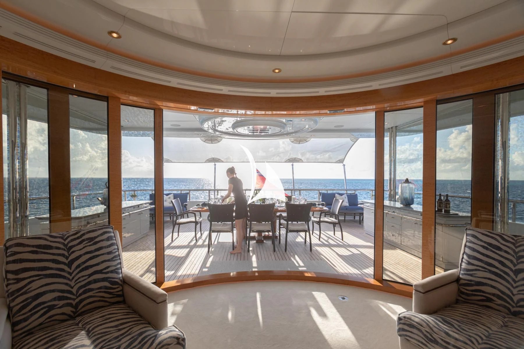 a person sitting at a table in a room with large windows aboard LUCKY LADY Yacht for Sale