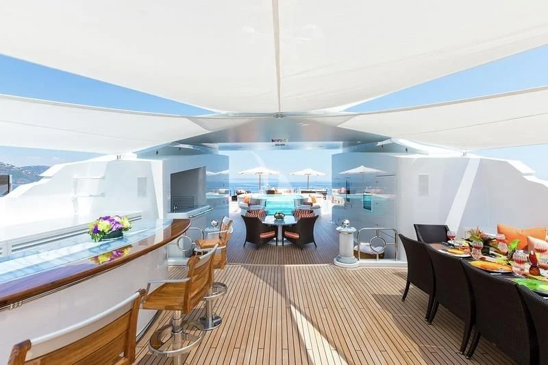a room with a large window and a table with chairs and a tv aboard LUCKY LADY Yacht for Sale