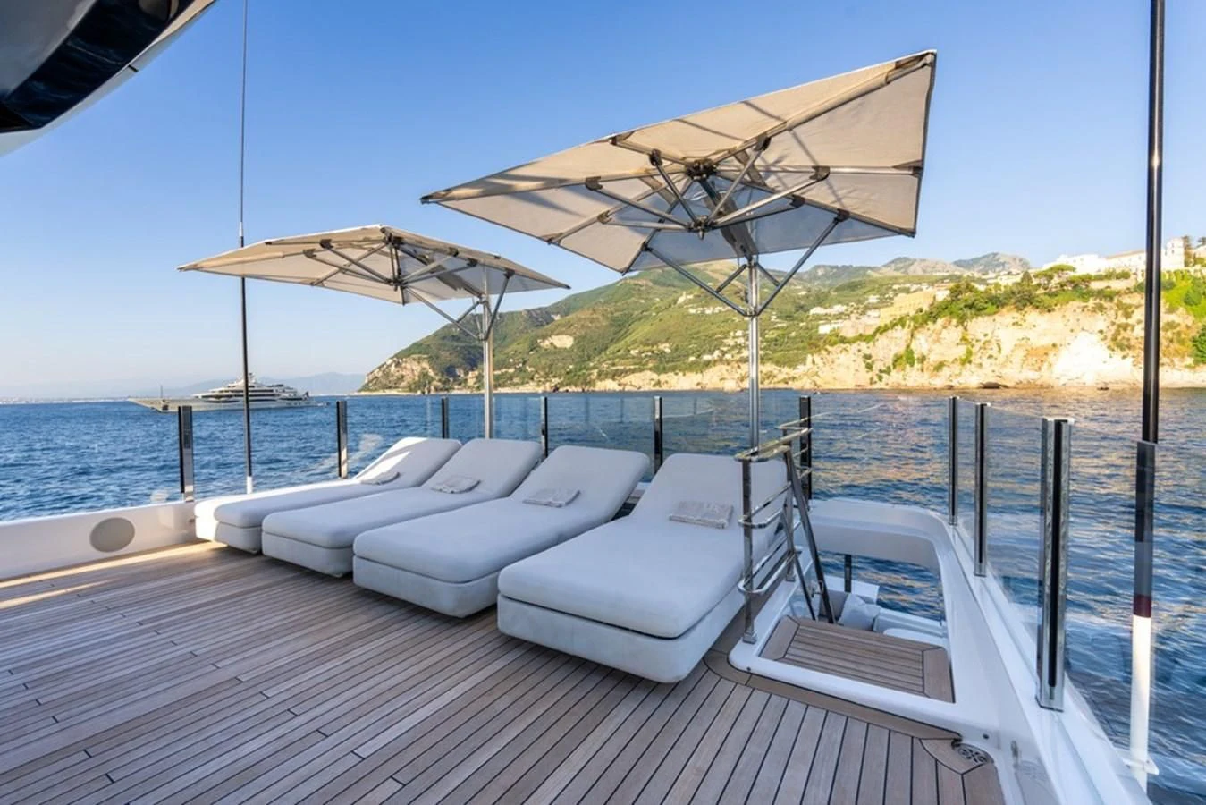 a lounge area with lounge chairs and umbrellas on a deck aboard ASANTE Yacht for Sale