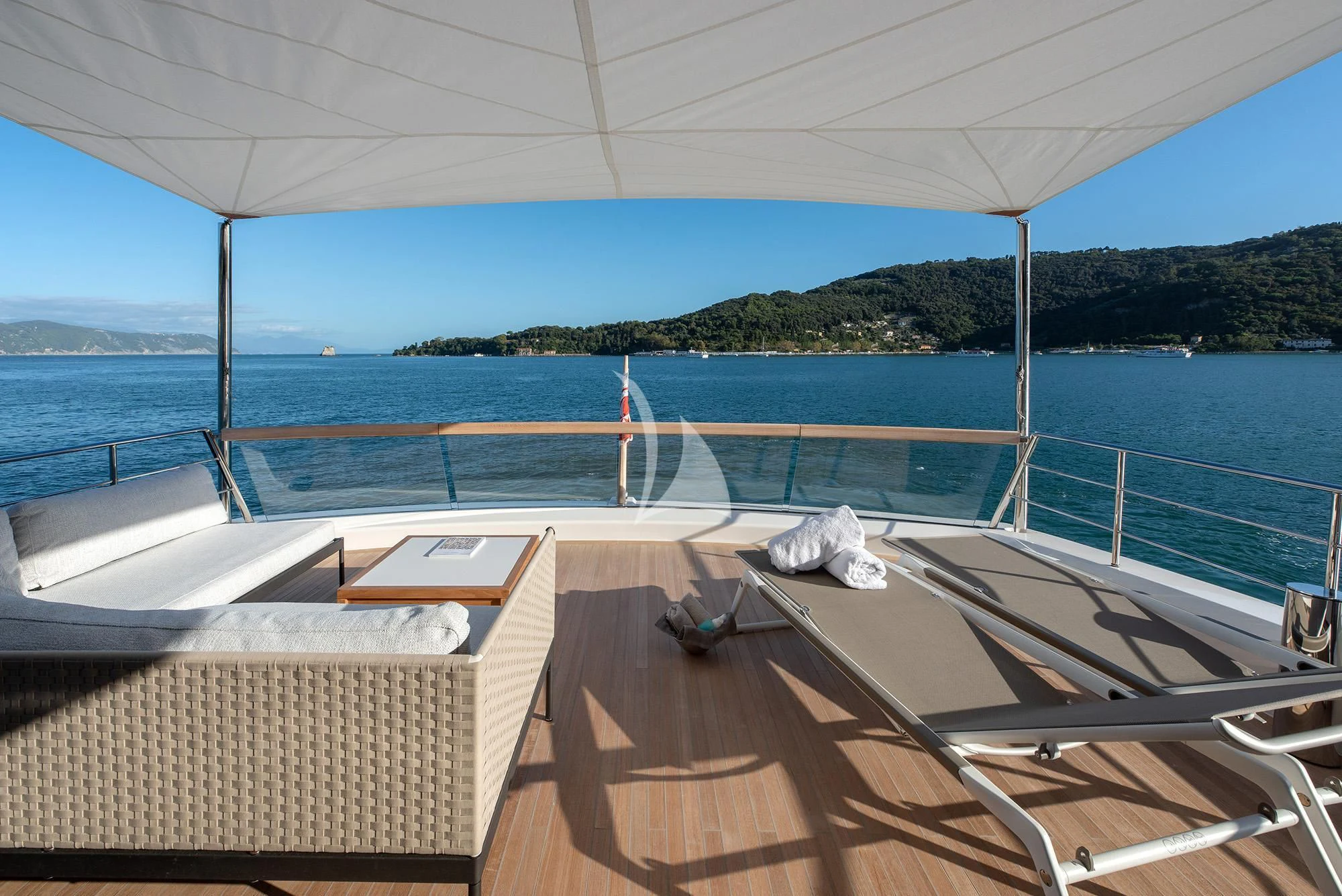 a deck with a view of the ocean and mountains in the background aboard TIBERIAS Yacht for Sale