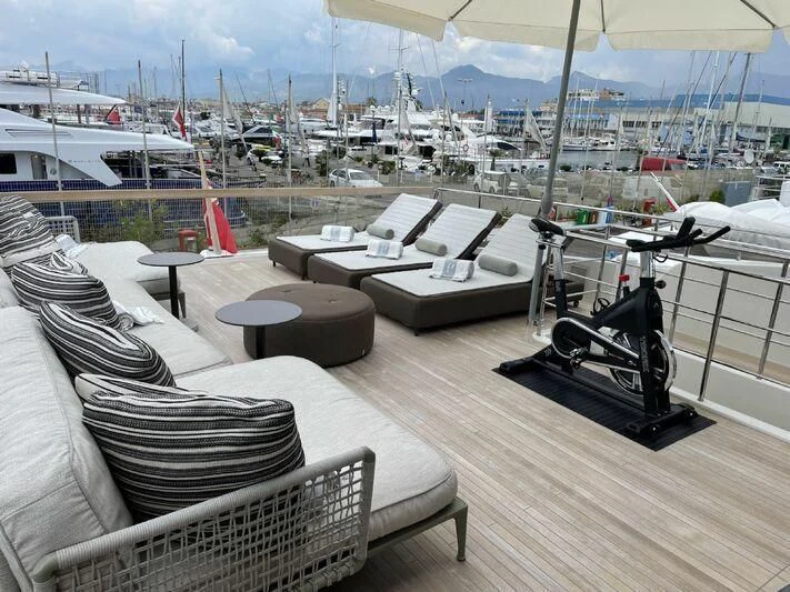 a deck with a deck overlooking a marina with boats and a large city aboard PIACERE III Yacht for Sale