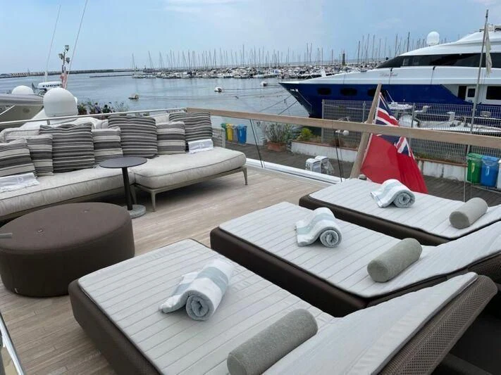 a deck with a bed and a table on it aboard PIACERE III Yacht for Sale