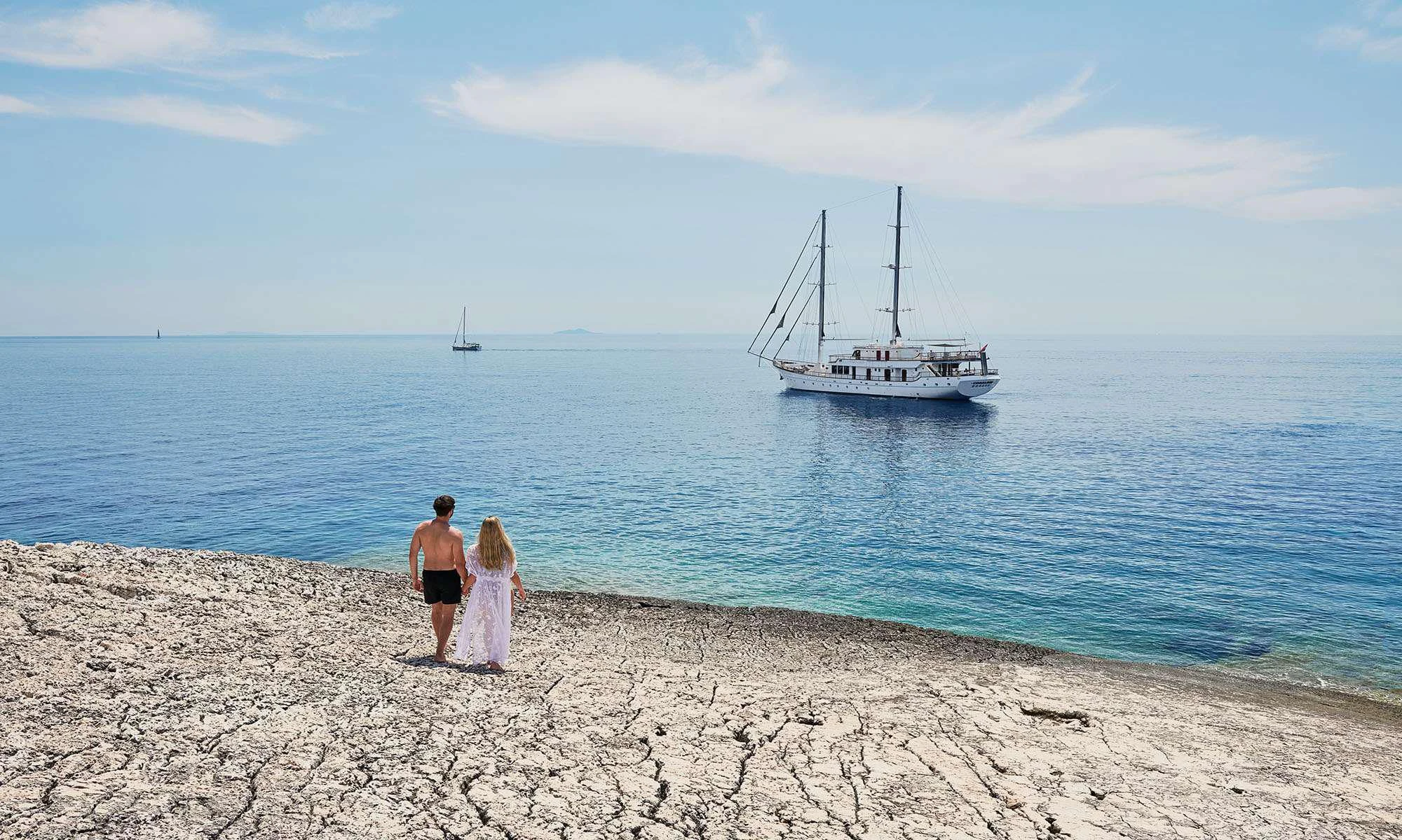 a man and woman on a beach aboard CORSARIO Yacht for Charter