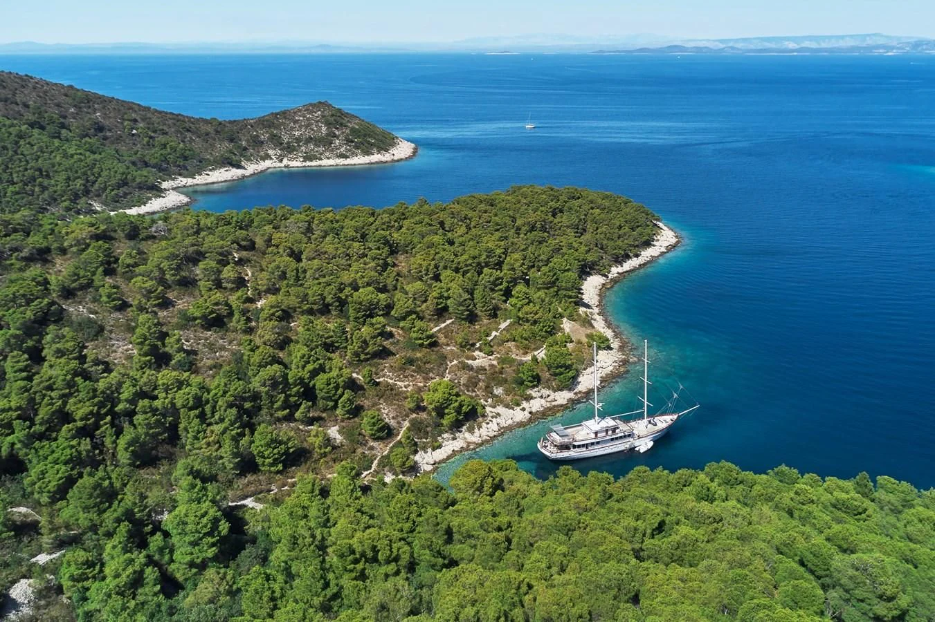 a large island with trees and a boat in it aboard CORSARIO Yacht for Charter