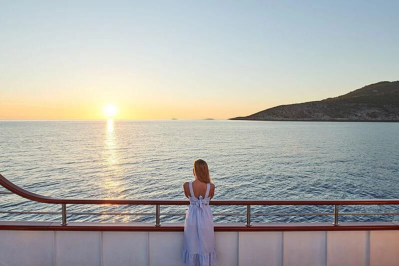 a person standing on a railing overlooking a body of water aboard CORSARIO Yacht for Charter