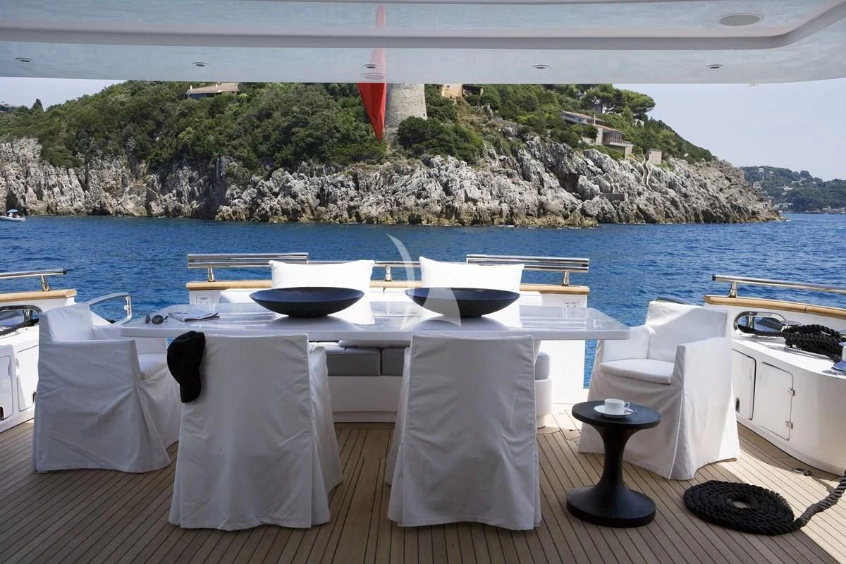 a table with chairs and a large body of water in the background aboard NIKCA Yacht for Sale