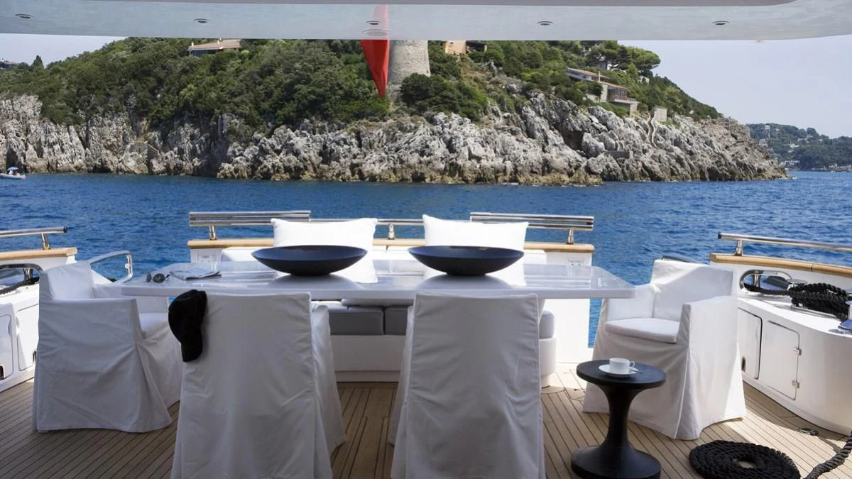 a table with chairs and a body of water in the background aboard NIKCA Yacht for Sale