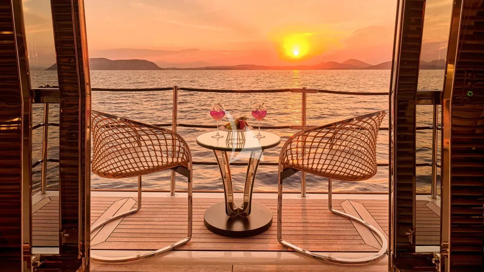 a table and chairs on a balcony overlooking a sunset aboard DALOLI Yacht for Charter