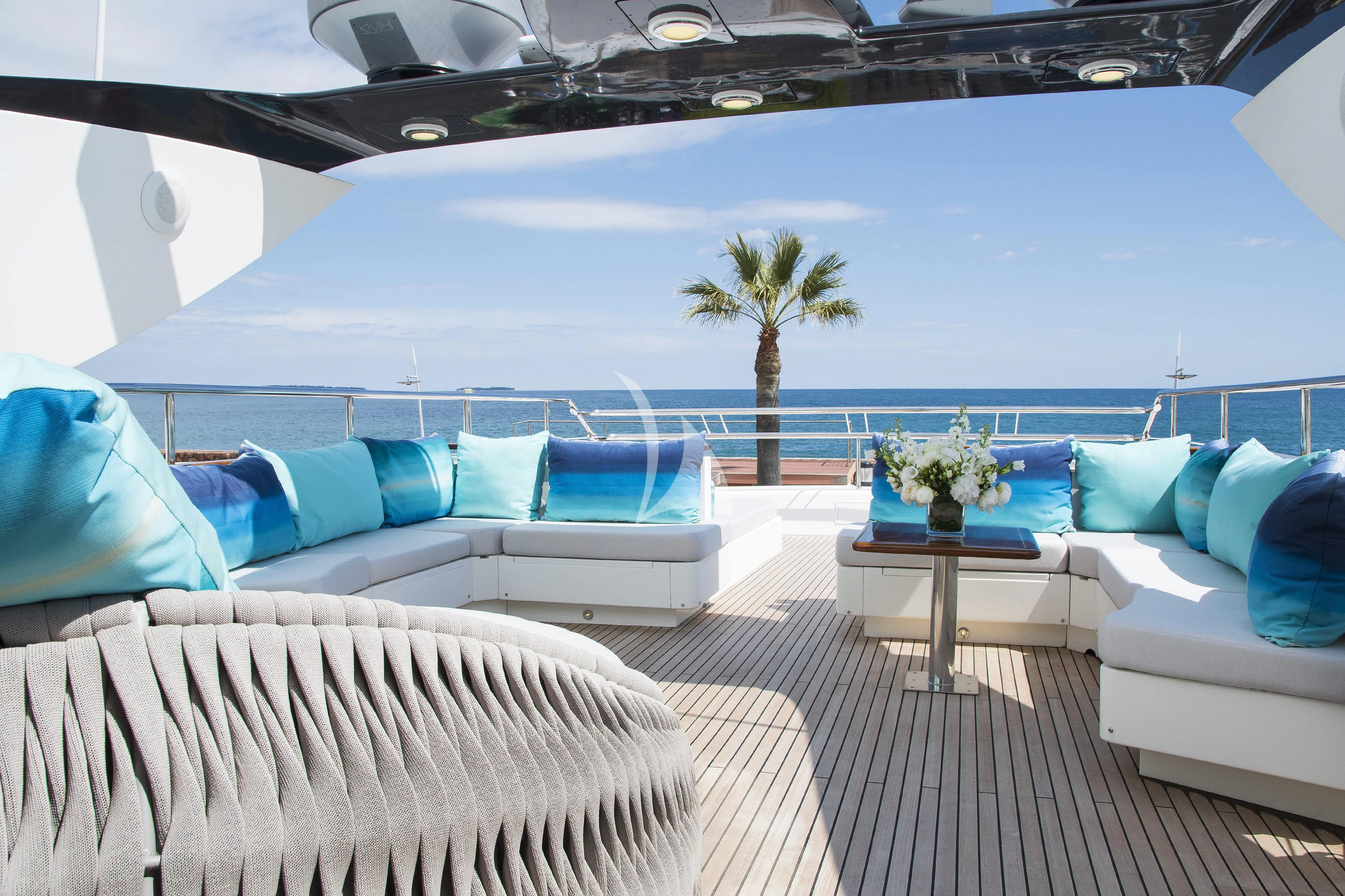a lounge area with a large blue lounge chair and a table with palm trees on it aboard LADY EMMA Yacht for Sale