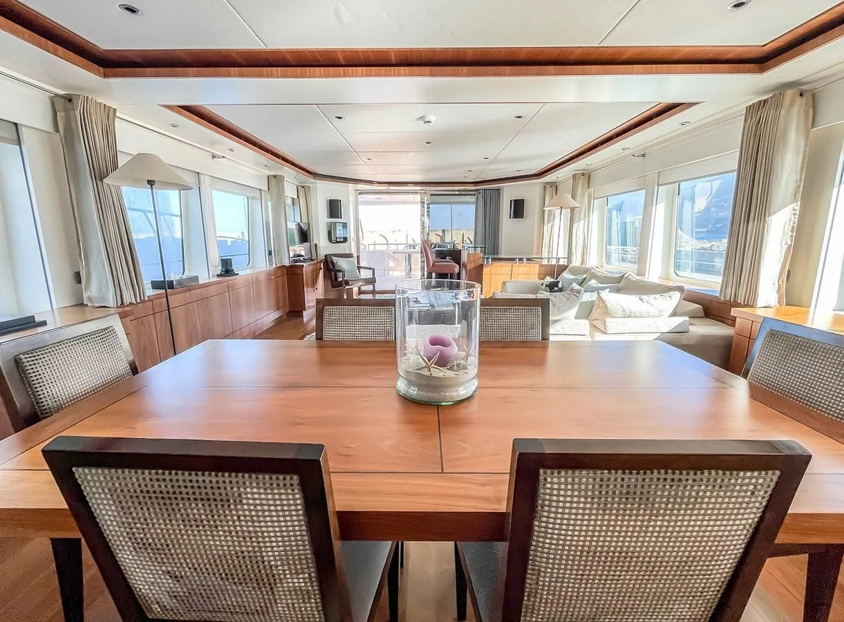 a large living room with a wood table and chairs aboard VERSE Yacht for Sale