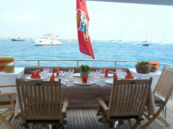 a table with chairs and a flag on it aboard VERSE Yacht for Sale