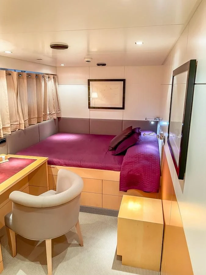 a bedroom with a bed and desk aboard VERSE Yacht for Sale