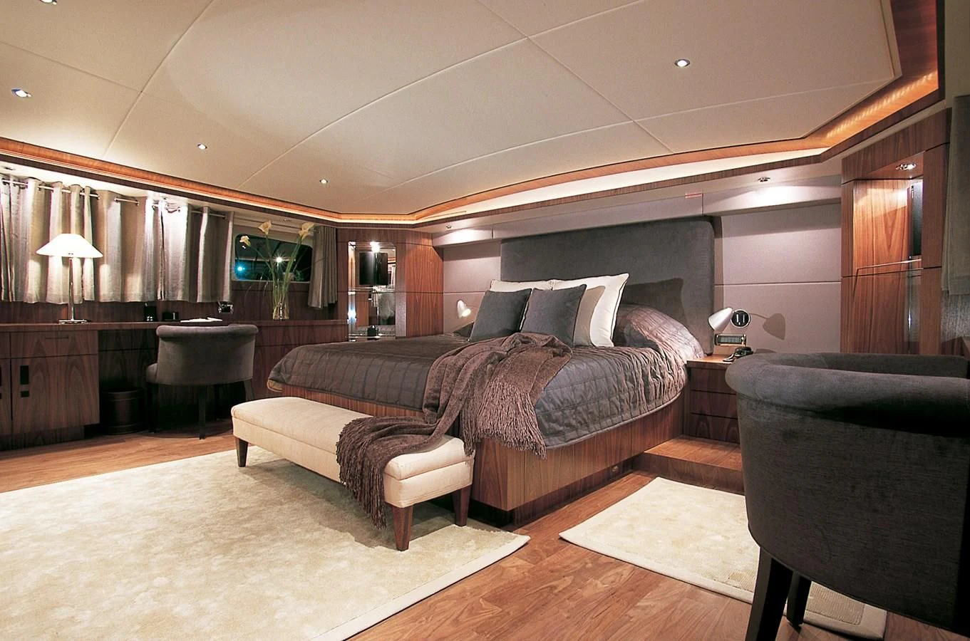 a large bedroom with a bed and a chair aboard VERSE Yacht for Sale