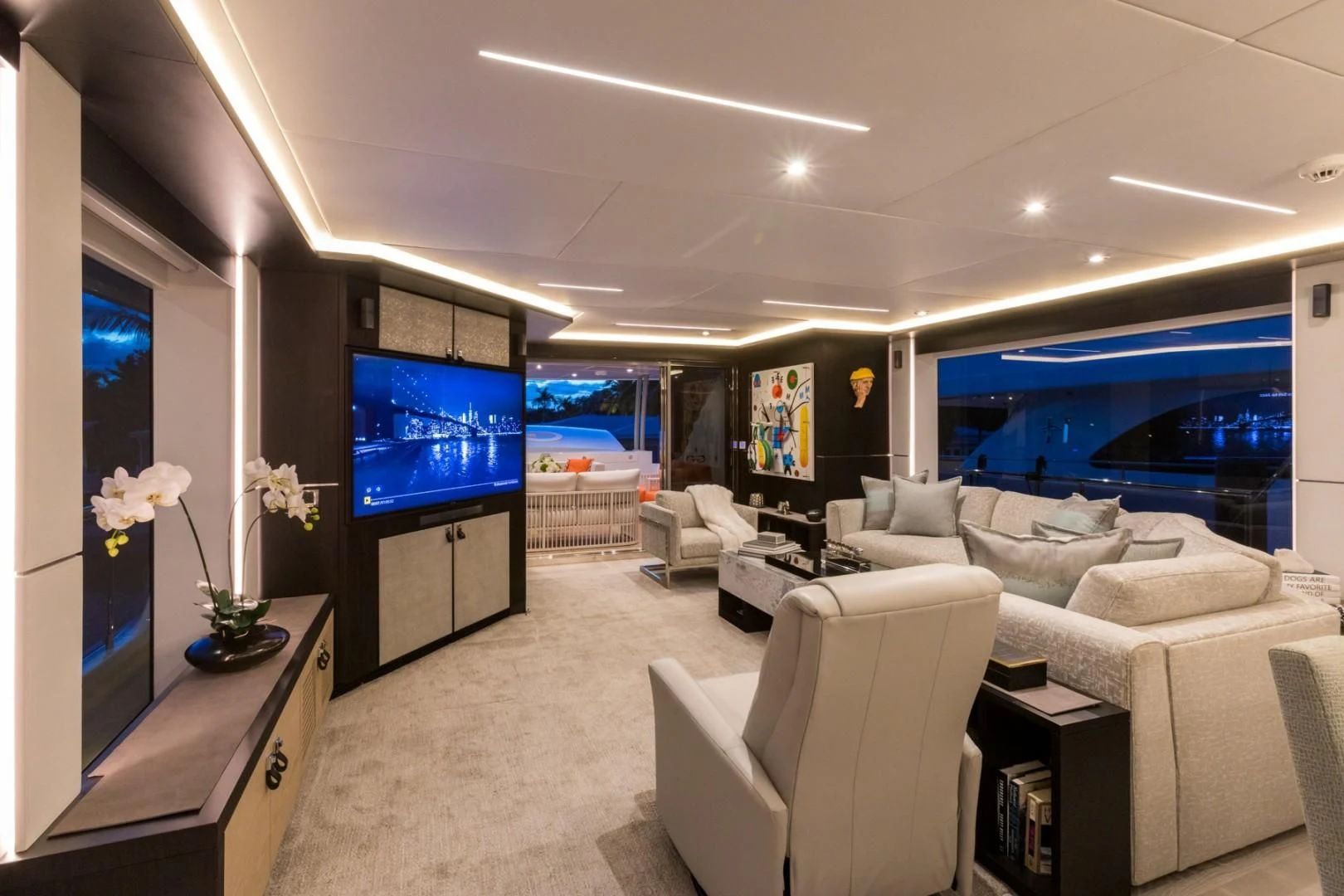 a living room with a large blue screen and white furniture aboard GG Yacht for Sale