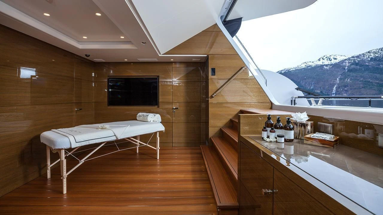 a room with a bed and a table with bottles and a window aboard EVENT Yacht for Sale