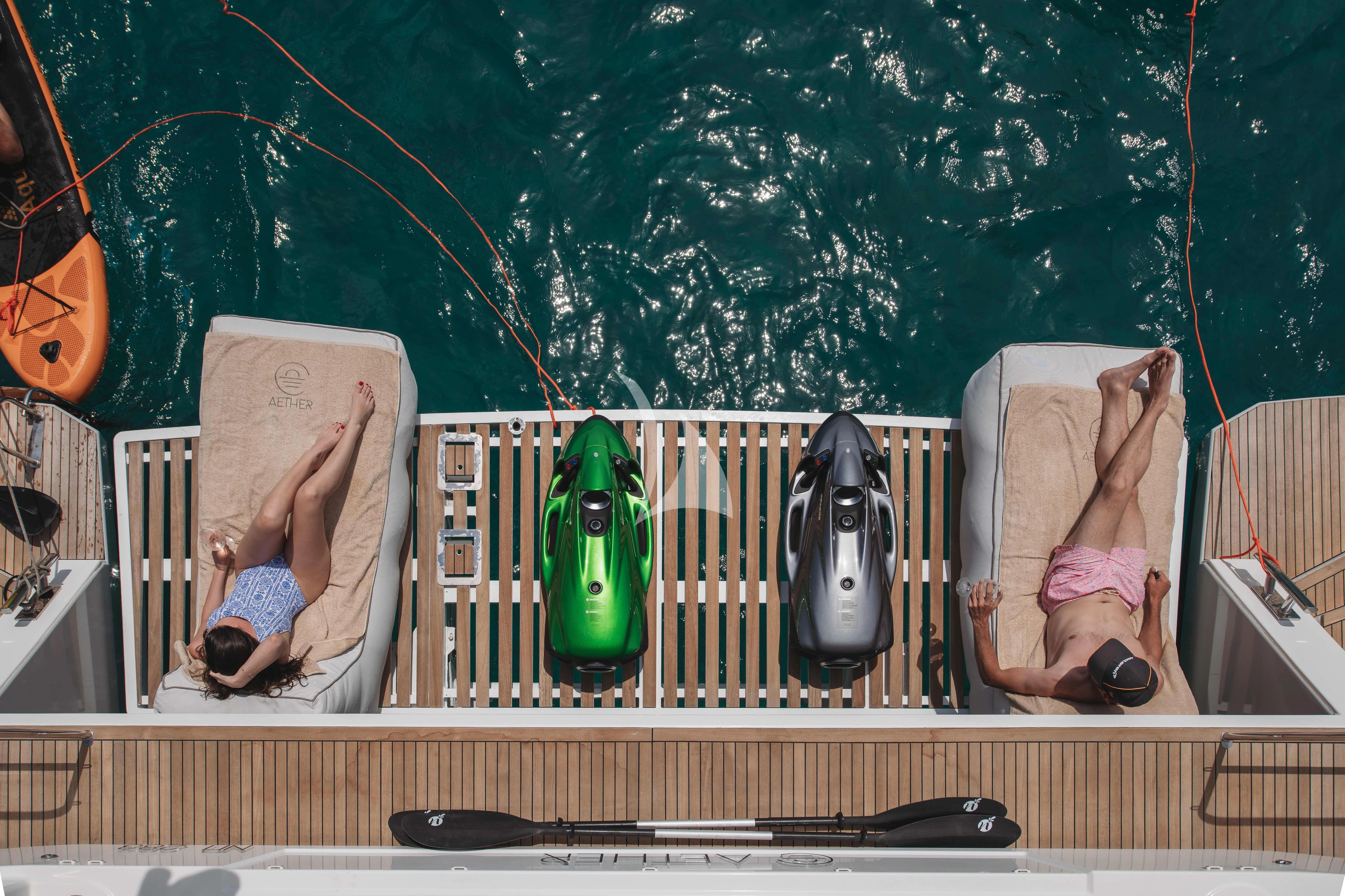 a person sitting on a bench next to a beer bottle and a guitar aboard AETHER Yacht for Charter