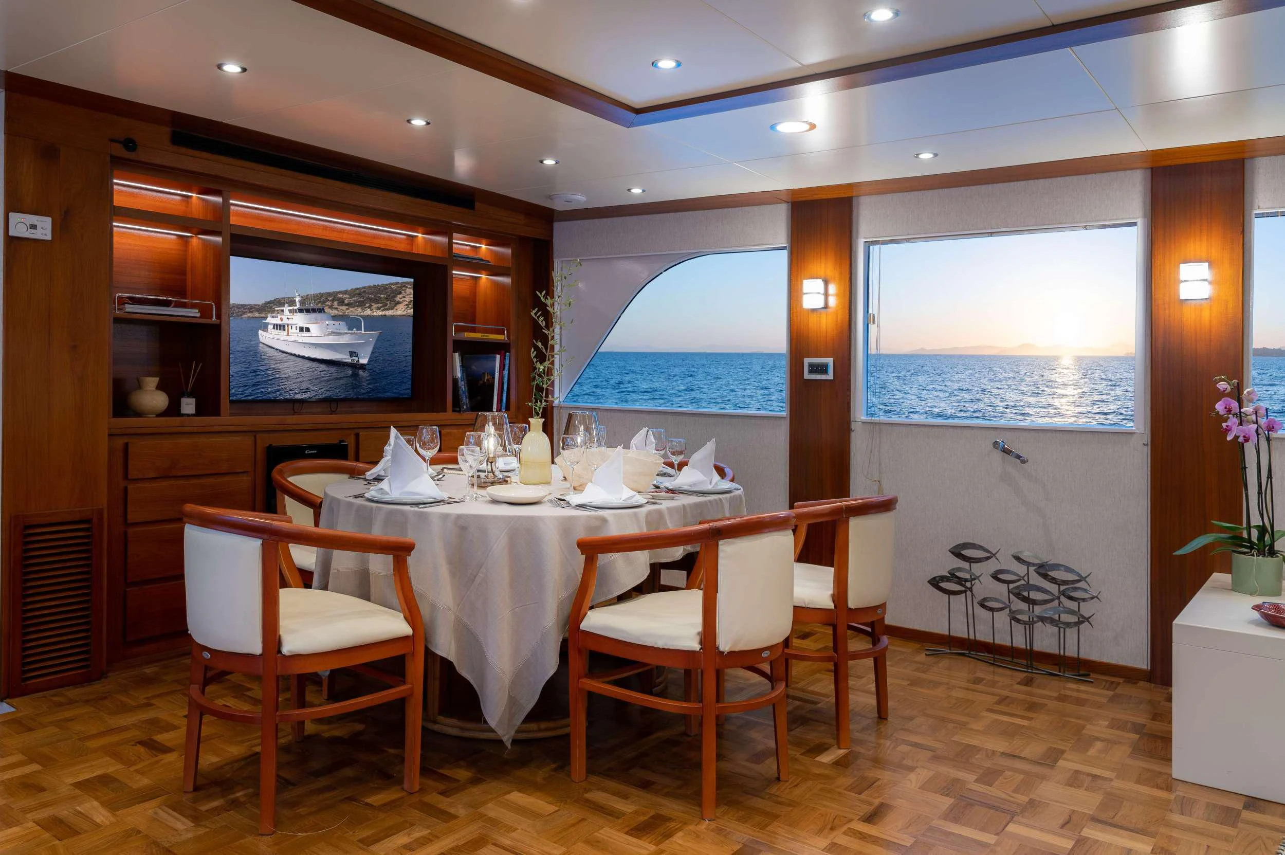 a dining table and chairs in a room with a large window aboard TAKA Yacht for Sale