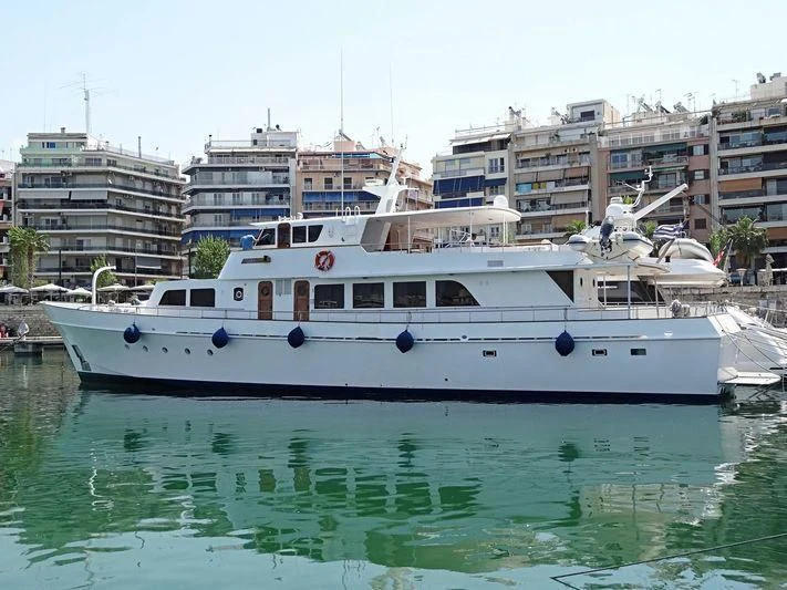 a white boat in a body of water with buildings in the background aboard TAKA Yacht for Sale