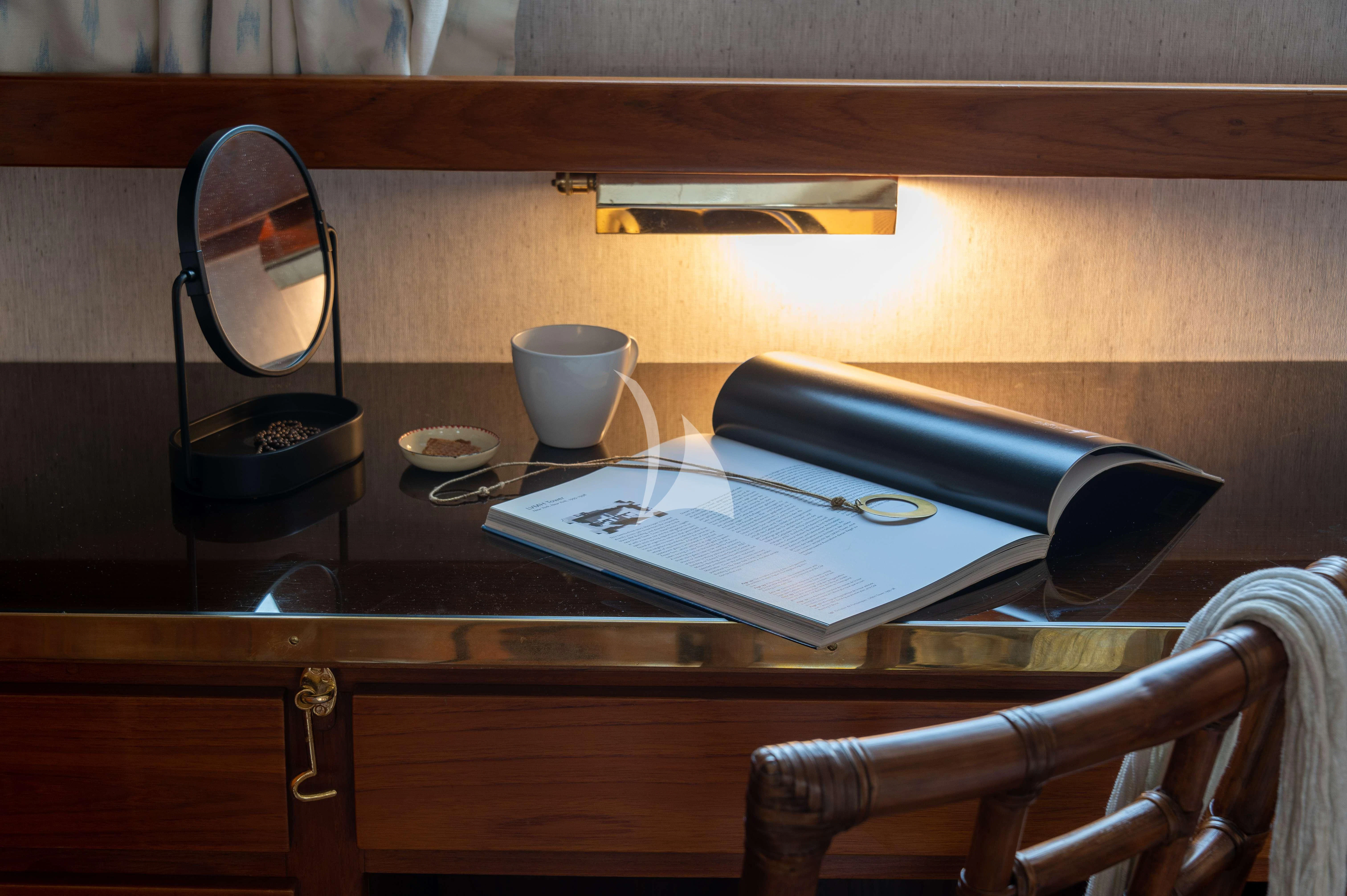 a desk with a mirror and a book on it aboard TAKA Yacht for Sale