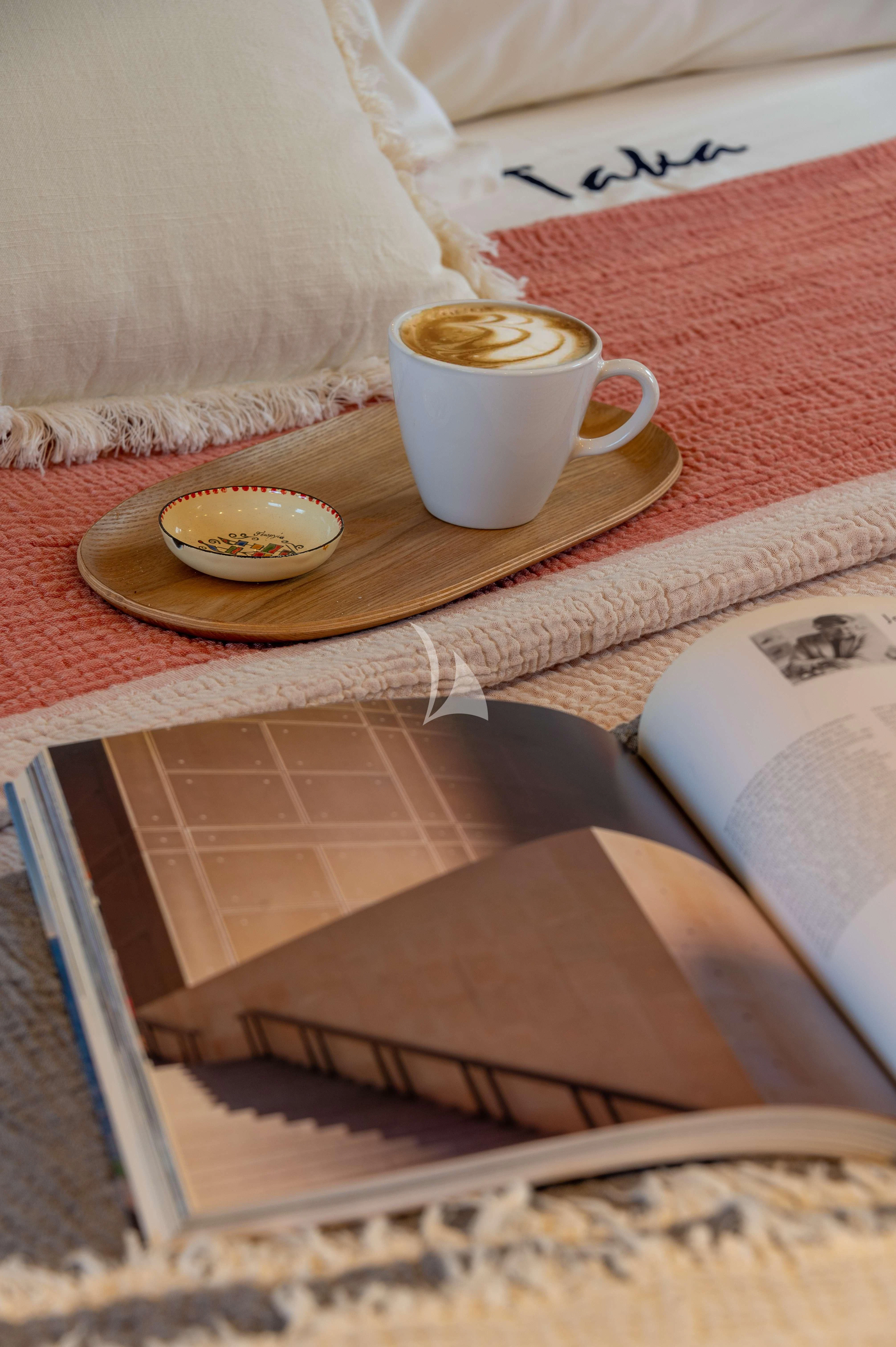 a book and a cup of coffee on a table aboard TAKA Yacht for Sale