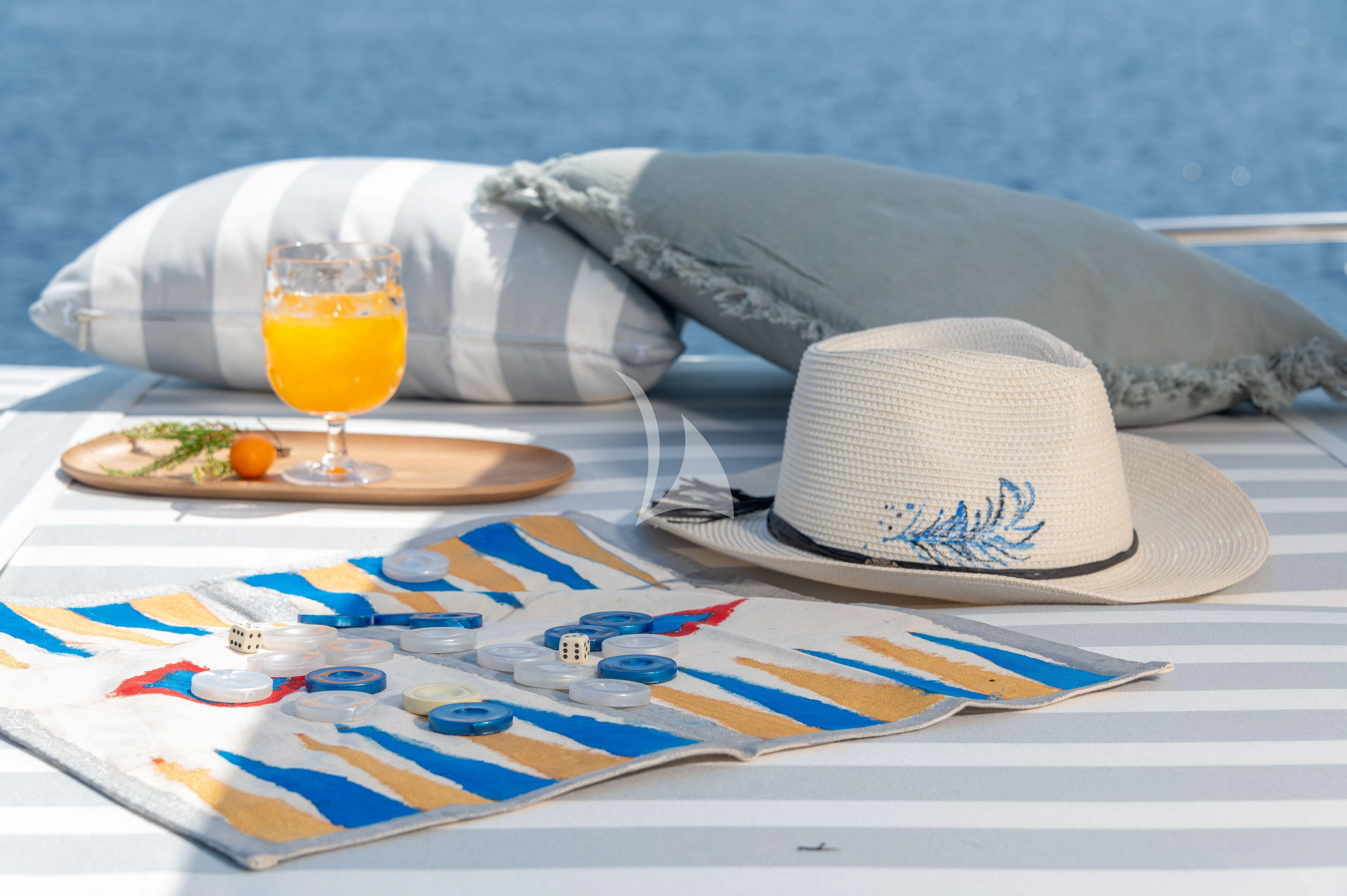 a hat and a plate of food on a beach aboard TAKA Yacht for Sale