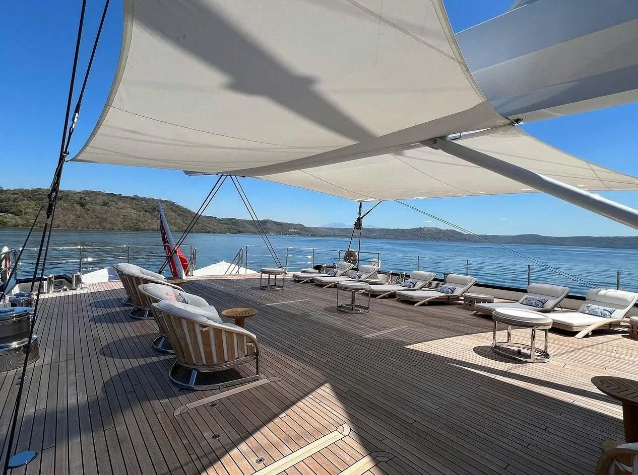 a deck with a view of the ocean and a large boat aboard SEA EAGLE Yacht for Sale