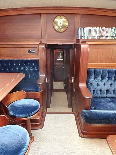 a room with a bookcase and chairs aboard ILIOS Yacht for Sale