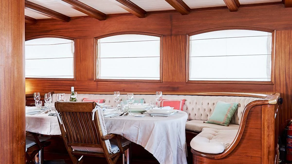 a dining table and chairs in a room with a window aboard QUEEN OF KARIA Yacht for Sale
