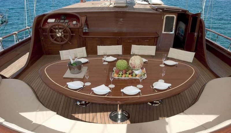 a table with chairs and a large wheel on it aboard QUEEN OF KARIA Yacht for Sale