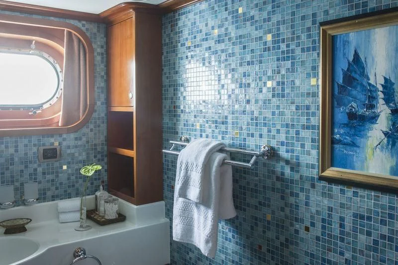 a bathroom with a blue tiled wall aboard RELENTLESS Yacht for Sale