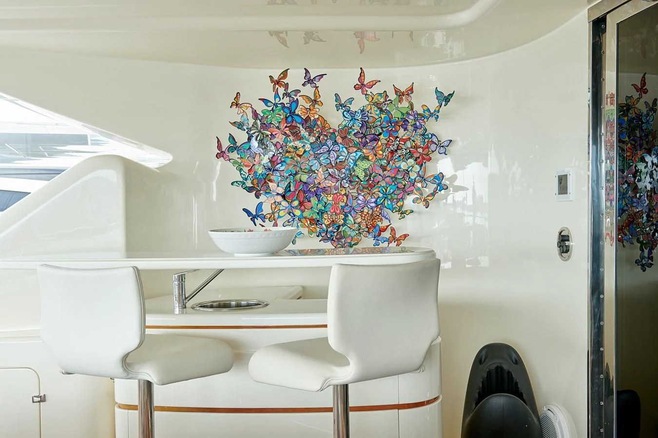 a white chair next to a white table with a bowl of flowers on it aboard BUNKER Yacht for Sale