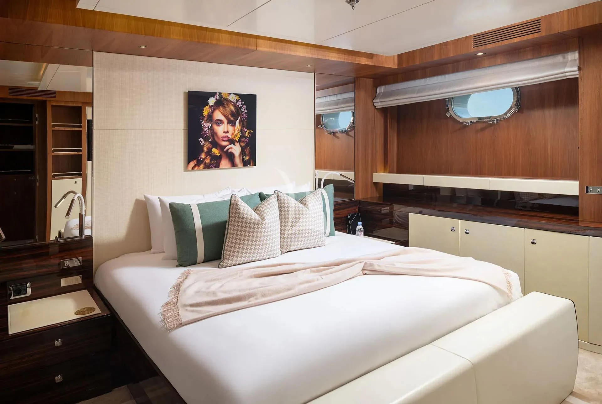 a bed with a white sheet and pillows in a room with a wood cabinet and a mirror aboard TALEYA Yacht for Sale