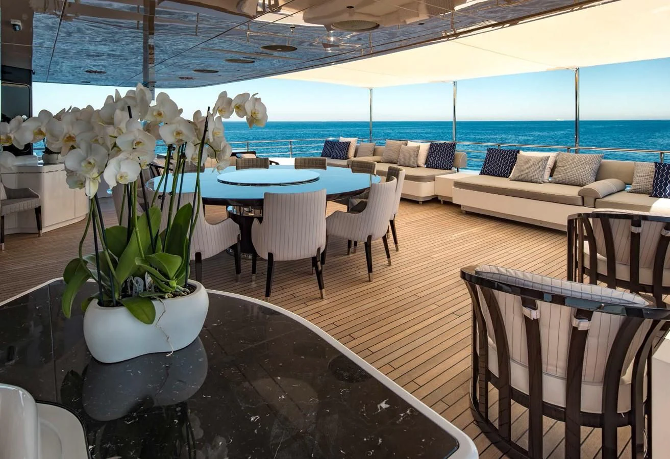 a vase of white flowers on a table in a room with a couch and chairs aboard TALEYA Yacht for Sale