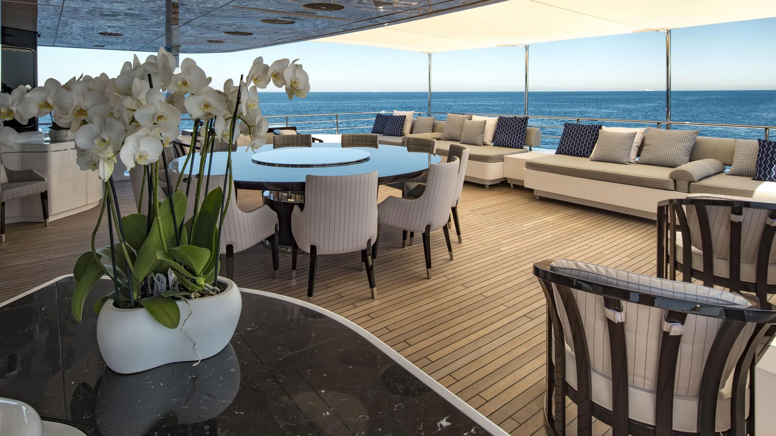 a vase of white flowers on a table with chairs and tables aboard TALEYA Yacht for Sale